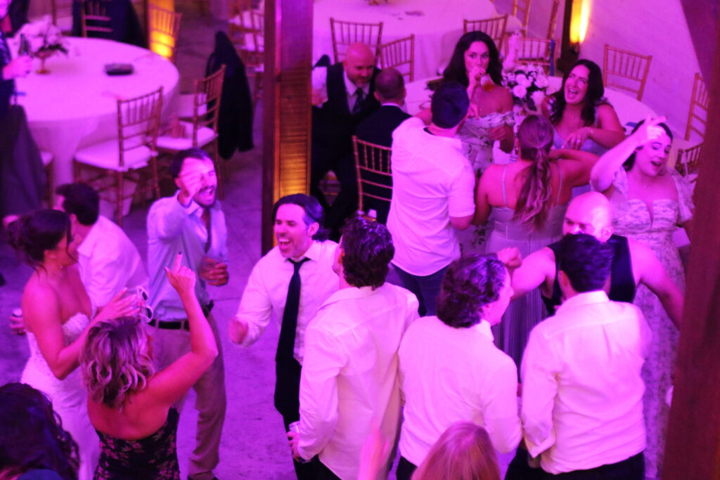 Wedding guests dancing as AURA DJ manages the reception schedule