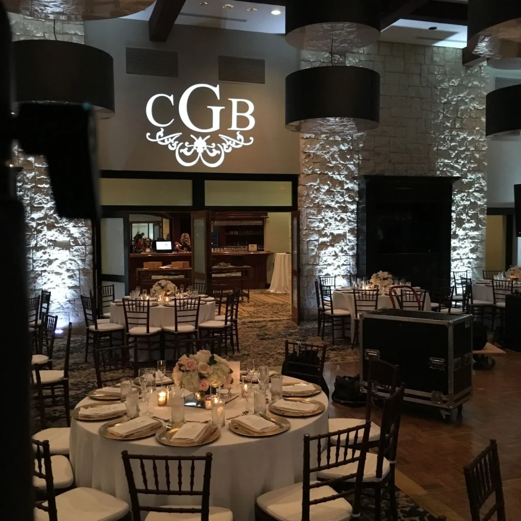 Elegant DJ wedding monogram projection on wall behind reception tables